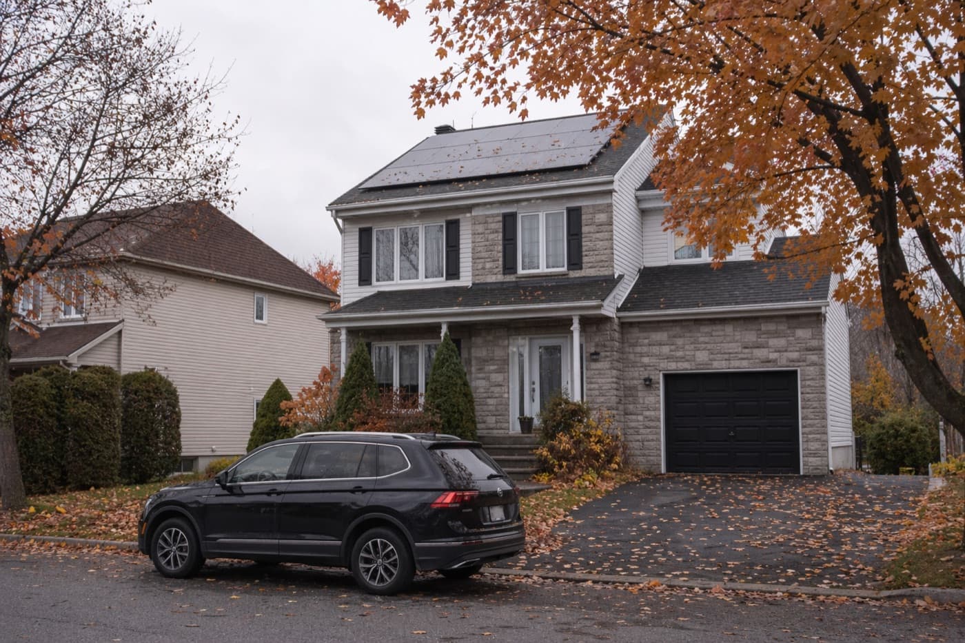 Unifamiliale pierre avec panneaux solaires en automne, région de Québec